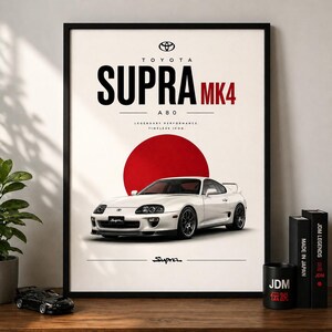 Puede incluir: Impresión enmarcada de un Toyota Supra MK4 blanco. La impresión tiene un fondo crema con un círculo rojo y el texto "SUPRA MK4 A80". El logotipo de Toyota y la palabra "Supra" también son visibles. La impresión está en un marco negro.