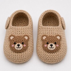 Puede incluir: Un par de zapatillas de beb&eacute; de ganchillo beige. Cada zapatilla presenta una cara de oso marr&oacute;n con mejillas rosas, una nariz y ojos negros. Las zapatillas tienen una peque&ntilde;a correa lateral y est&aacute;n dise&ntilde;adas para la comodidad y el calor.