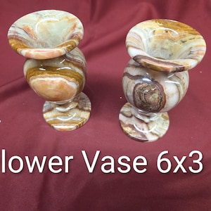 May include: Two decorative flower vases. Each vase is made of a stone material with a swirling pattern of brown, beige, and cream colors. The vases are approximately 6 inches tall and 3 inches wide.