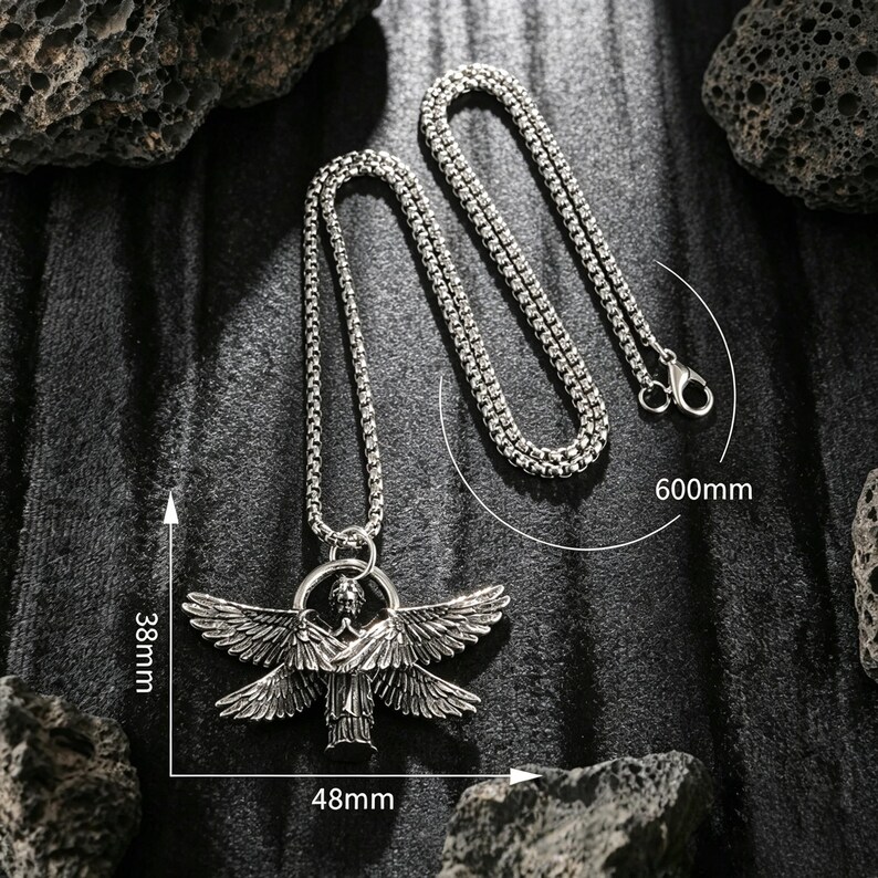 May include: Silver necklace with a pendant depicting a winged figure. The pendant is 48mm wide and 38mm high. The chain is 60cm long. The necklace is shown on a dark, textured background.