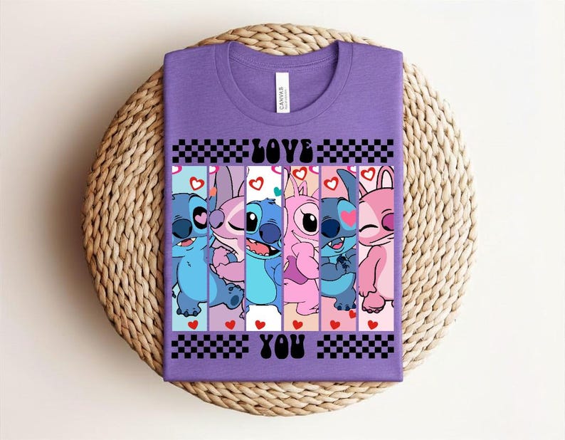 May include: A purple t-shirt featuring a graphic design with the text "LOVE YOU" and cartoon characters. The design includes blue, pink, and purple characters with hearts and checkered patterns.