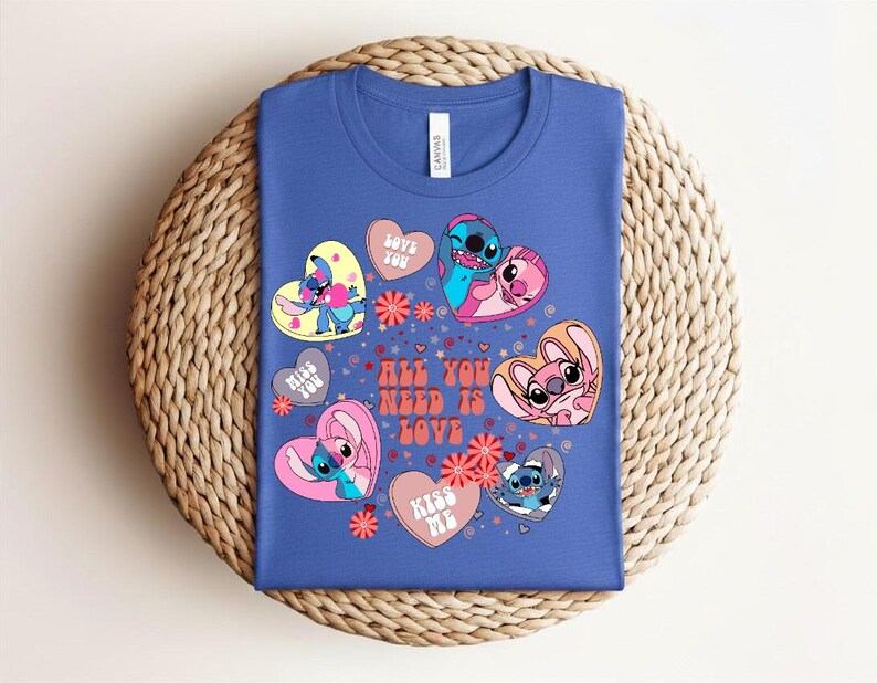 Peut inclure: Un t-shirt bleu avec un motif color&eacute; de personnages de dessins anim&eacute;s en forme de c&oelig;ur. Le motif comprend le texte "ALL YOU NEED IS LOVE" et des phrases comme "LOVE YOU" et "KISS ME".