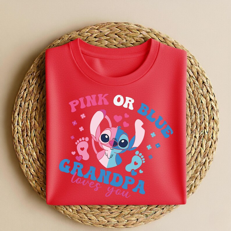 Pu&ograve; includere: Una maglietta rossa girocollo con una grafica di un personaggio dei cartoni animati, divisa in rosa e blu, con la scritta "PINK OR BLUE GRANDPA loves you". Il design include cuori, fiori e impronte.