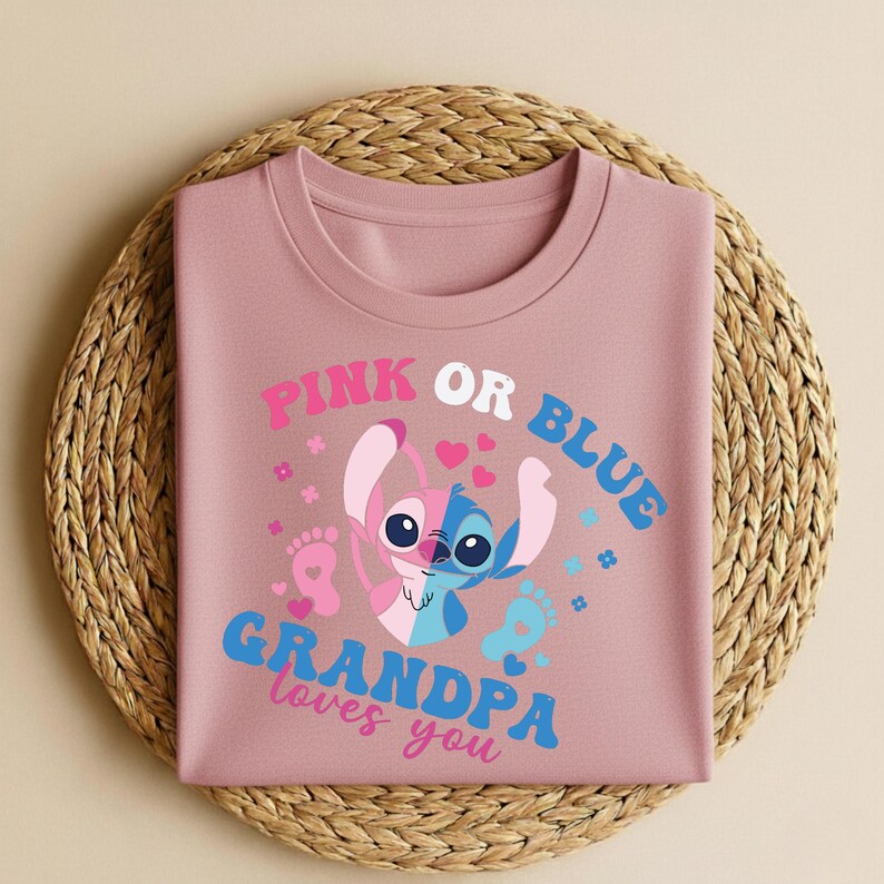 Pu&ograve; includere: Una maglietta color rosa antico con la scritta "PINK OR BLUE GRANDPA loves you". La grafica presenta un personaggio dei cartoni animati bicolore, rosa e blu, con cuori e impronte. La maglietta &egrave; piegata su un sottobicchiere circolare intrecciato.