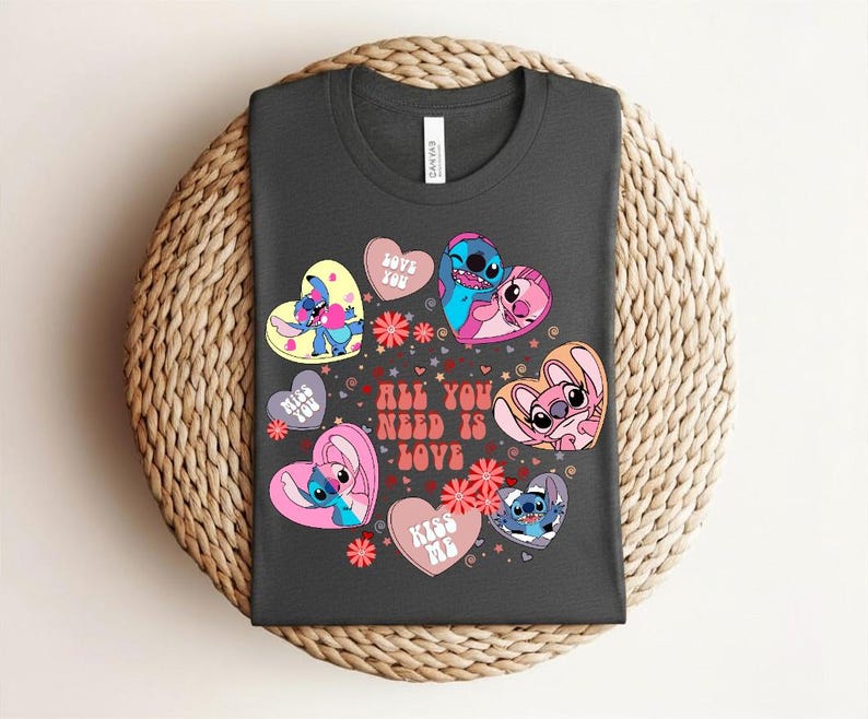 Peut inclure: T-shirt gris fonc&eacute; avec des personnages de dessins anim&eacute;s dans des c&oelig;urs. Les c&oelig;urs sont roses, jaunes et blancs, avec les textes "Love You" et "Kiss Me". Le t-shirt porte &eacute;galement l'inscription "All You Need Is Love" en rouge.