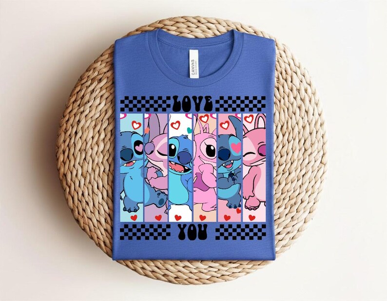 May include: Blue t-shirt featuring a graphic of cartoon characters in shades of blue and pink, with the words "LOVE YOU" in black. The design includes hearts and a checkered pattern.