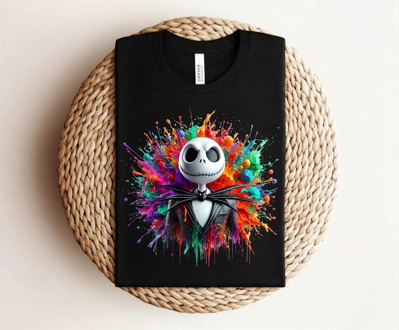 May include: A black t-shirt featuring a graphic of a white skeletal character with a stitched mouth and large eye sockets, wearing a black pinstripe suit and bow tie, set against a vibrant, multi-colored paint splatter background.