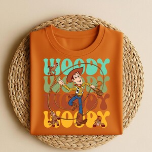 Peut inclure: Une tasse en c&eacute;ramique blanche avec une anse noire et le texte "But First, Coffee" en noir, en gras. La tasse est pos&eacute;e sur une surface en bois. La tasse mesure environ 10 cm de haut.