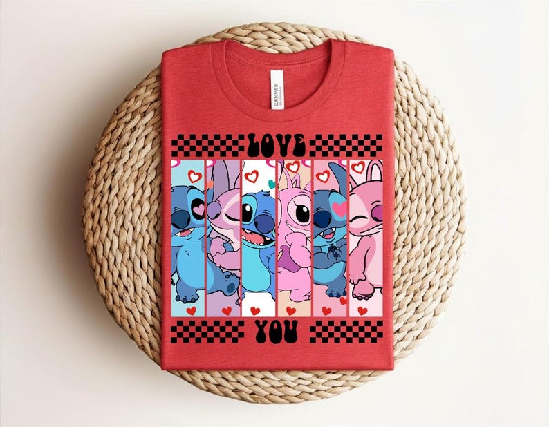 May include: Red t-shirt featuring a graphic of cartoon characters in shades of blue and pink, with the words "LOVE YOU" in black. The design includes hearts and a checkered pattern. The shirt is displayed on a woven, circular surface.