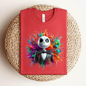 May include: A red crew neck t-shirt featuring a graphic of a white skeletal character with a black pinstripe suit and bow tie, centered against a vibrant, multi-colored paint splatter background with hues of blue, green, yellow, and pink.