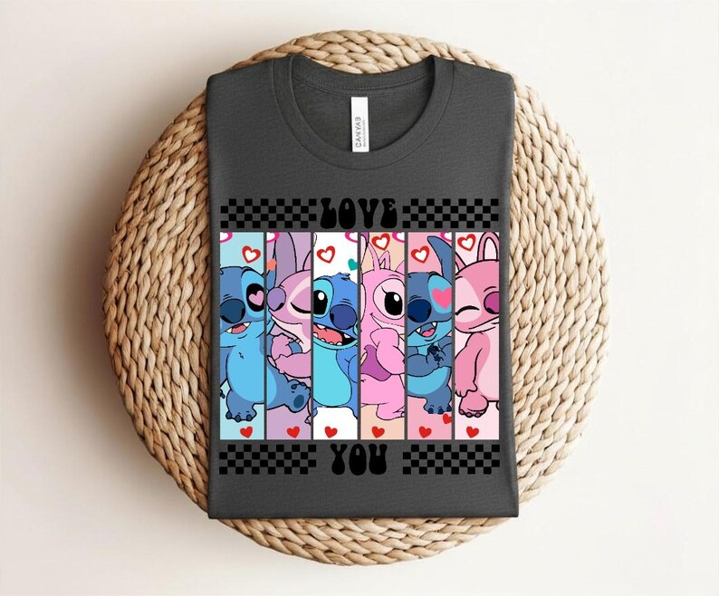 May include: Dark gray t-shirt featuring a colorful graphic of cartoon characters with the text "LOVE YOU" in black. The design includes blue, pink, and purple characters with hearts and a checkered pattern.