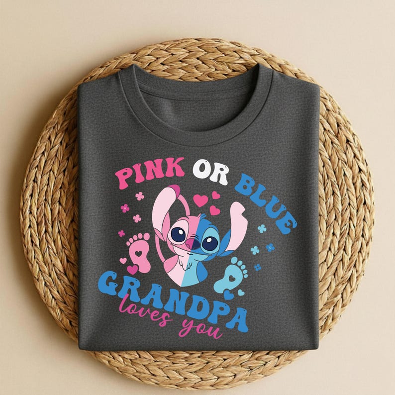 Pu&ograve; includere: T-shirt grigio scuro con un personaggio dei cartoni animati diviso in rosa e blu, con la scritta "PINK OR BLUE" sopra e "GRANDPA loves you" sotto. Il design include cuori, impronte e dettagli floreali.