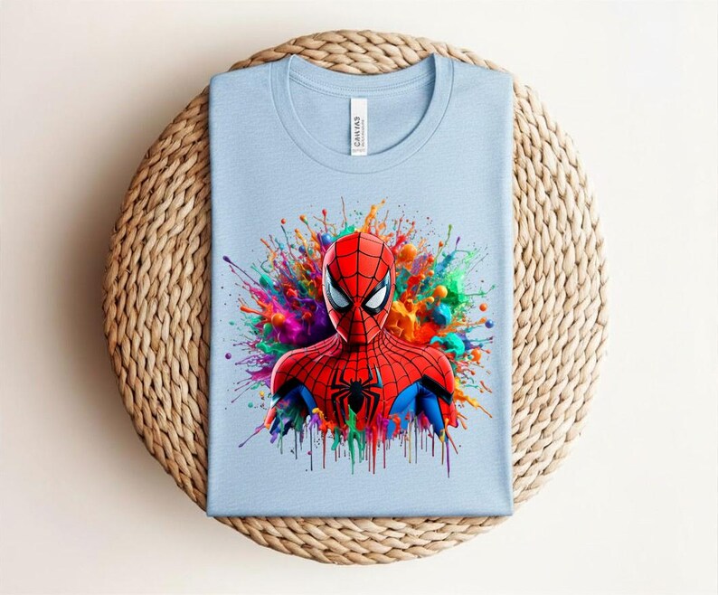 Op de afbeelding: Lichtblauw T-shirt met een Spider-Man afbeelding. De superheld is afgebeeld in zijn rood-zwarte pak, omringd door kleurrijke verfspatten. Het T-shirt is gemaakt van een zachte stof.