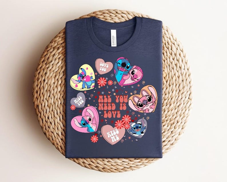 Peut inclure: T-shirt bleu marine avec des personnages de dessins anim&eacute;s en forme de c&oelig;ur. Le texte "ALL YOU NEED IS LOVE" est visible, ainsi que d'autres phrases. Le motif comprend des fleurs roses et rouges.