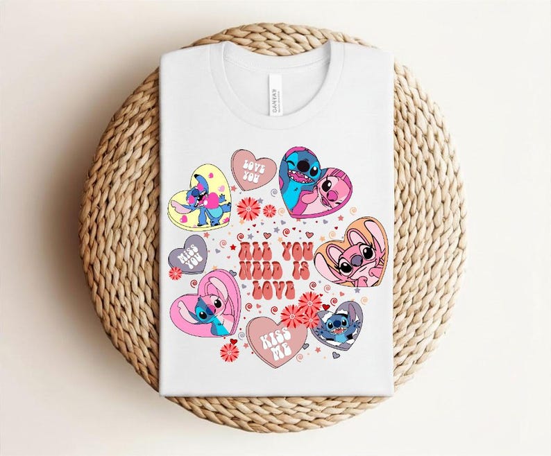 Peut inclure: T-shirt blanc avec un motif color&eacute; de personnages de dessins anim&eacute;s en forme de c&oelig;ur. Le motif comprend le texte "All You Need Is Love", ainsi que des phrases comme "Love You" et "Kiss Me".