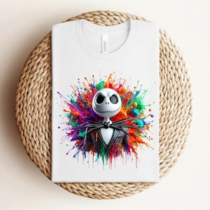 May include: A white t-shirt featuring a graphic print of a skeletal character with a round white head and a black pinstriped suit. The character is centered against a vibrant, multi-colored paint splatter background with hues of red, blue, green, and yellow.