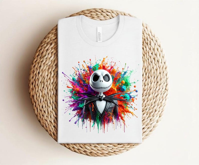 May include: A white t-shirt featuring a graphic print of a skeletal character with a round white head and a black pinstriped suit. The character is centered against a vibrant, multi-colored paint splatter background with hues of red, blue, green, and yellow.