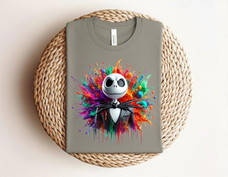 May include: A grey t-shirt featuring a graphic of a white skull character with a black pinstripe suit and bow tie, centered against a vibrant, multi-colored paint splatter design with hues of pink, blue, orange, green, and yellow.