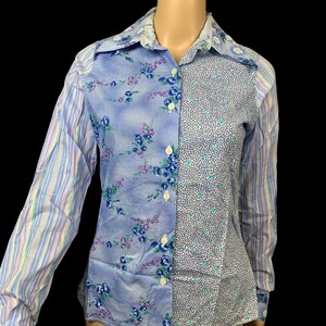 May include: A long-sleeve button-down shirt featuring a patchwork design. The front panels display a blue floral print on one side and a small-scale blue and white leaf pattern on the other. The sleeves feature a vertical multi-coloured stripe pattern.