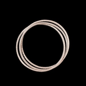 May include: Three silver bangles with a textured design, stacked on top of each other.