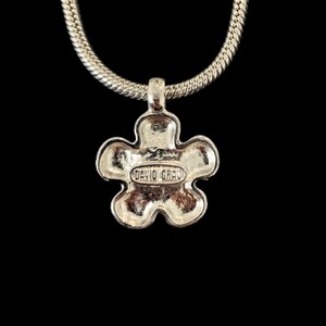 May include: Silver chain necklace with a silver flower pendant. The back of the pendant has the words "David Yurman" engraved on it.