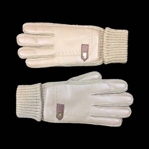May include: A pair of beige leather gloves with a knitted cuff. The gloves have a brown leather accent on the back of the hand.