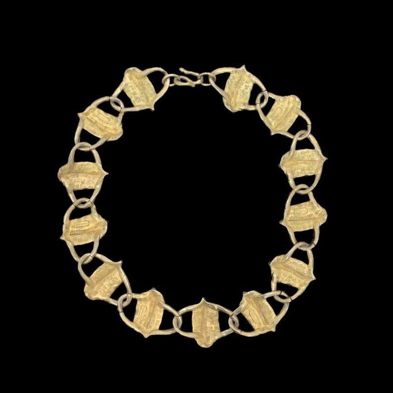May include: A gold-toned necklace composed of a series of repeating shield-shaped links connected by small circular rings. The metal surface features a textured, matte finish throughout the entire piece, which is secured with a simple hook clasp.