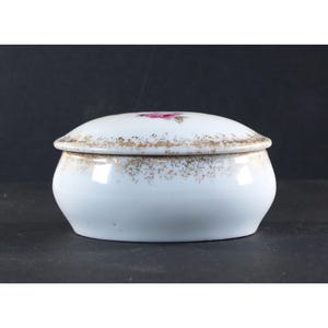 May include: White porcelain trinket box with a gold rim and a single pink rose painted on the lid.