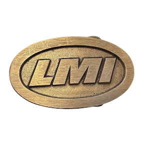 May include: A gold-toned oval belt buckle with the letters "LMI" embossed in a bold, sans-serif font.
