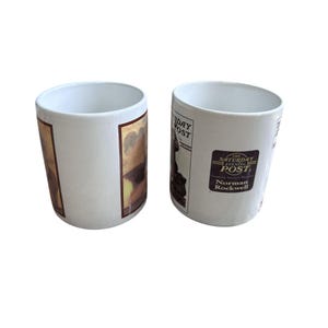 Pu&ograve; includere: Due tazze in ceramica bianca. Una tazza presenta un'illustrazione vintage con toni marroni e gialli. L'altra tazza ha un adesivo con il testo "The Saturday Evening Post" e "Norman Rockwell".