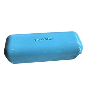 May include: A white ceramic mug with a black handle and the text "But First, Coffee" in a bold, black font. The mug is set against a blurred background, suggesting a cozy setting.