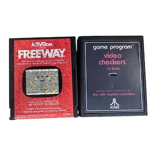 May include: Two vintage Atari game cartridges. The red cartridge is for "Freeway" by Activision. The black cartridge is for "Video Checkers" by Atari. Both cartridges have text and graphics.