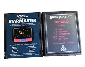 Könnte beinhalten: Zwei Vintage Atari-Spielmodule. Eines ist mit "StarMaster" mit einer Weltraumgrafik beschriftet. Das andere ist "Combat" mit einer Liste von Spielmodi. Beide sind schwarz mit farbenfrohem Text und Grafiken.