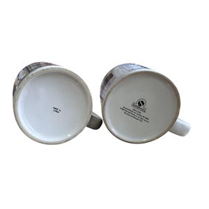 Pu&ograve; includere: Due tazze in ceramica bianca con un design a paesaggio urbano. Le tazze hanno manici bianchi e il fondo di una tazza recita "Made in China". L'altra tazza ha il logo e il testo di Sherwood Brands.