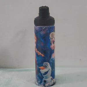 Pu&ograve; includere: Una borraccia cilindrica con tappo nero, decorata con personaggi del film Frozen. Il design presenta Elsa, Anna e Olaf su sfondo blu. La borraccia &egrave; adatta per bevande fredde.
