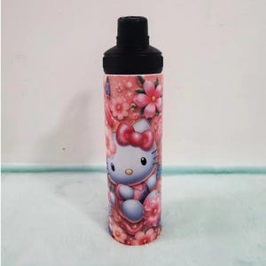 May include: A tall, insulated water bottle featuring a black cap and a pink floral design. The bottle is adorned with a cartoon image of Hello Kitty, surrounded by pink flowers. The design wraps around the entire bottle.