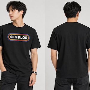 Peut inclure: Un t-shirt noir à manches courtes et col rond avec un motif sur la poitrine portant le texte 95.5 KLOS à l'intérieur d'une bordure rectangulaire arrondie soulignée de bleu, jaune et rouge. Le dos du t-shirt est noir uni sans motif.