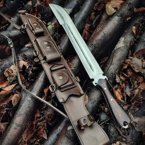 May include: A fixed-blade knife with a curved silver steel blade and a dark wood handle, accompanied by a brown leather sheath featuring multiple small storage pouches, brass-coloured snap fasteners, and an adjustable leather carrying strap.