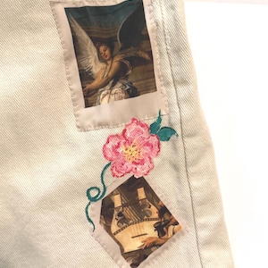 アップサイクルされた古着のミドル丈ベージュショートパンツ。縫い付けられたアートパッチとペイントされた花柄が特徴。