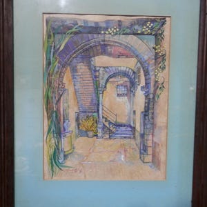 Puede incluir: Una pintura en acuarela enmarcada que representa una escena arquitectónica con arcos de piedra, una escalera y vegetación trepadora. La obra presenta tonos cálidos amarillos y marrones, acentos azules y una firma en la esquina inferior izquierda, todo dentro de un marco de madera oscura.