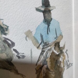 Puede incluir: Una pintura de acuarela sobre papel texturizado que representa a una figura con un sombrero de ala ancha y una camisa azul claro, montada sobre un caballo marrón. La obra utiliza pinceladas sueltas y expresivas para definir al jinete.