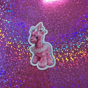 May include: A white ceramic mug with a black handle and the text "But First, Coffee" in a black, handwritten-style font. The mug is on a white surface.