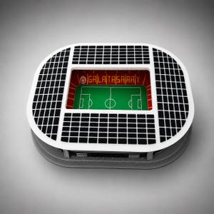 Może przedstawiać: Miniaturowy model stadionu z zielonym boiskiem do piłki nożnej, białymi sekcjami siedzeń w czarną kratkę oraz czerwonymi ścianami wewnętrznymi z napisem GALATASARAY żółtymi literami i okrągłym logo po lewej stronie.