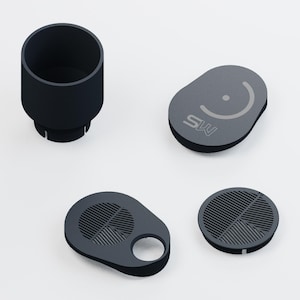 May include: A set of dark gray components including a cylindrical container, an oval lid with a circular icon and the text MS, a teardrop-shaped piece with a circular cutout and a grid pattern, and a circular grid insert with a small notch.
