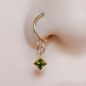 ペリドットのドロップが付いた金張りのダングルノーズリング。22ゲージ、20ゲージ、18ゲージのダングルチャームが付いた繊細なシームレスノーズピアス。