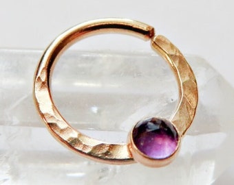 May include: A rose gold hammered hoop earring with a small purple amethyst gemstone.