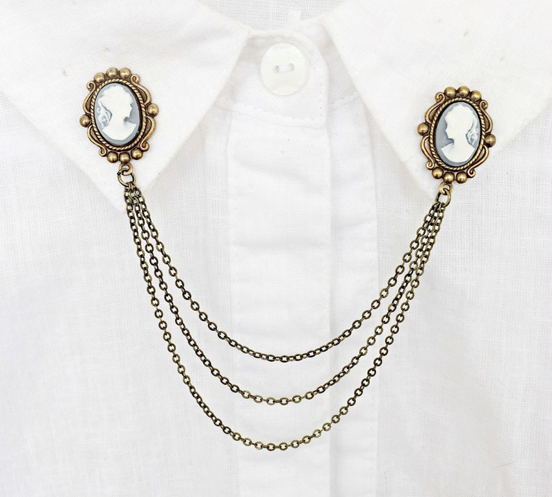 Op de afbeelding: Een gouden kraagspeld met een cameo met het profiel van een vrouw. De speld is bevestigd aan een ketting met drie strengen.