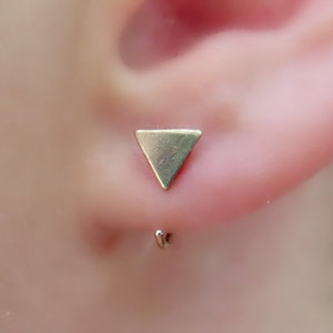 May include: A gold triangle earring with a curved post.