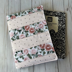 May include: A floral fabric notebook cover with a pink background and black polka dots. The cover features a rose pattern and is next to a composition notebook with the text "POSITION BOOK".