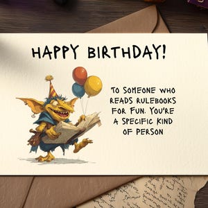 Könnte beinhalten: Geburtstagskarte mit der Aufschrift "HAPPY BIRTHDAY!". Die Karte zeigt eine Illustration eines Kobolds, der ein Buch und Luftballons hält. Der Text darunter lautet: "TO SOMEONE WHO READS RULEBOOKS FOR FUN. YOU'RE A SPECIFIC KIND OF PERSON."